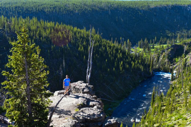 man on cliff over river at Yellowstone