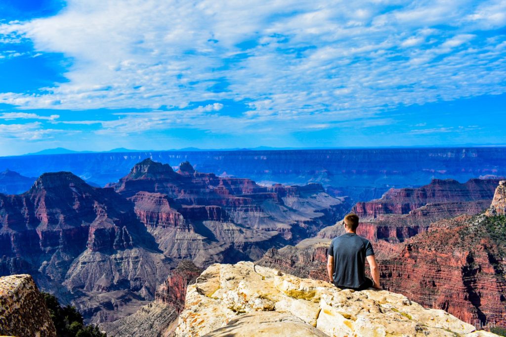 man sitting on the edge of the Grand Canyon at the north rim