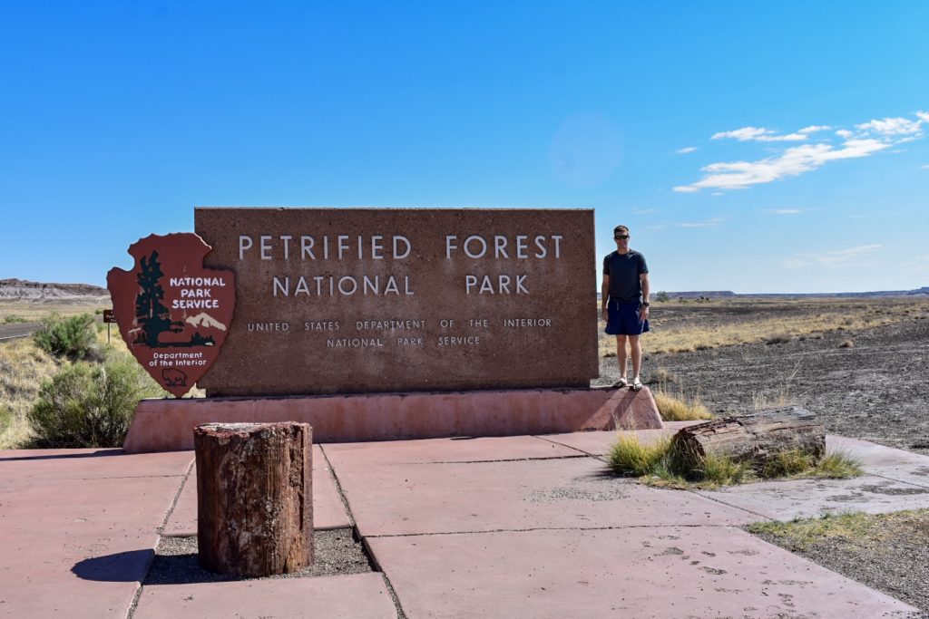 Guy standing at the entrance sign to petrified forest national park