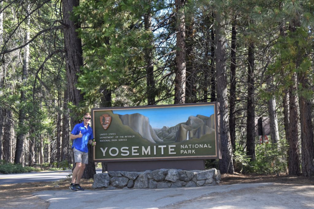 man in blue shirt standing at the entrance to Yosemite Valley national park