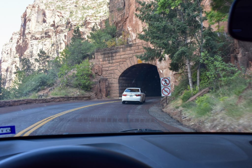 Car entering narrow tunnel through mountain in Utah