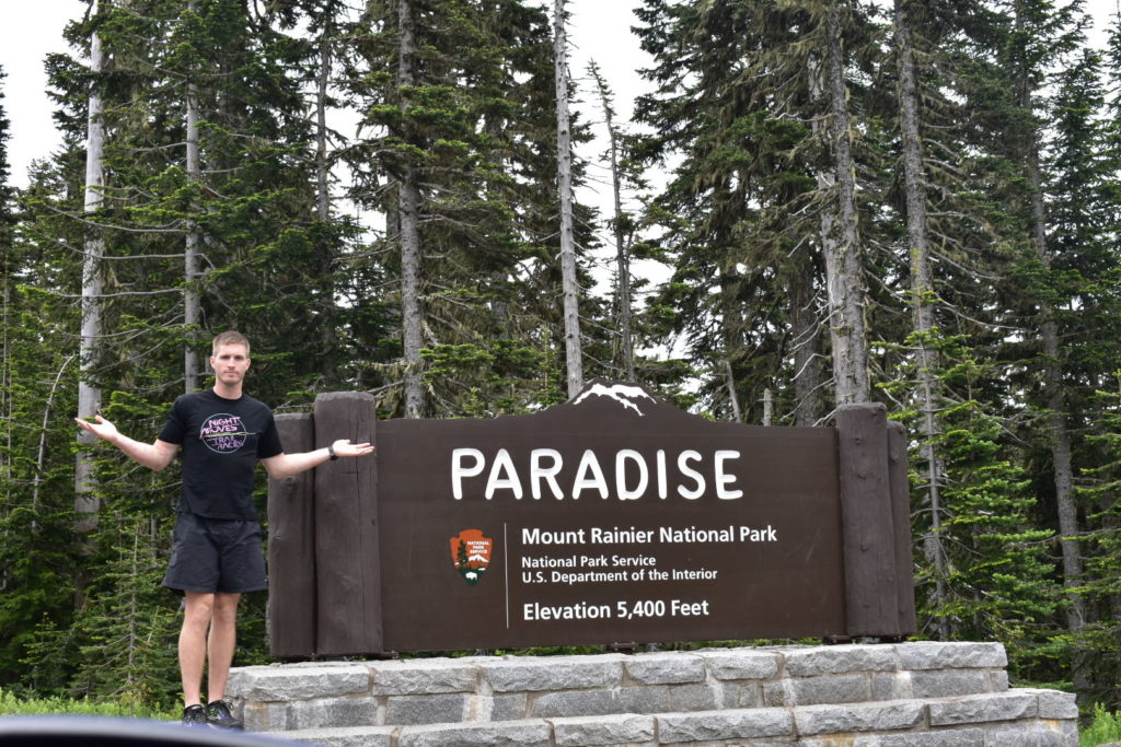 man in black shirt standing at paradise sign